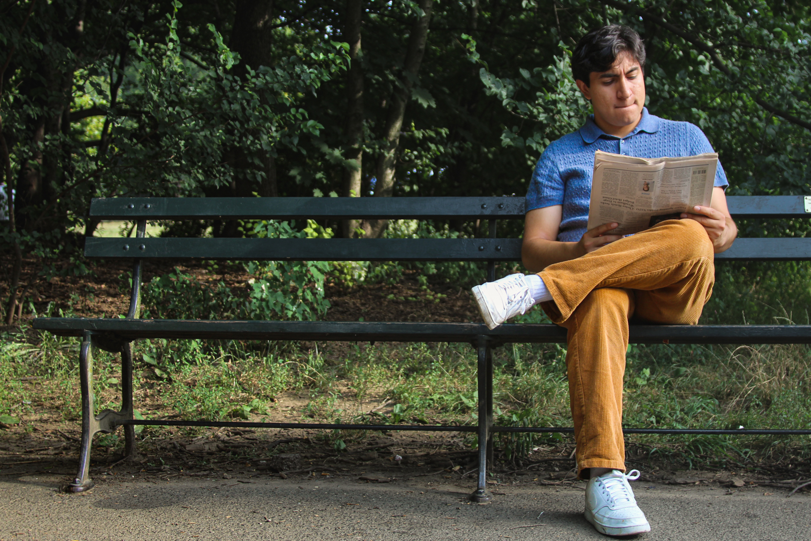 Chris Michael reading a newspaper on a park bench